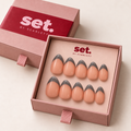 Silver Lining: Cool-grey French tips over a peach-nude base. Digitally styled packaging mockup based on Scarlett's photographed nail set.